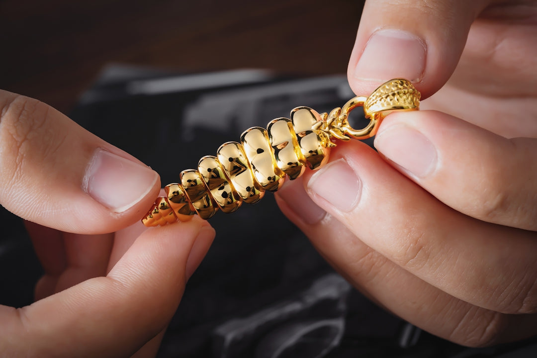 a person is holding a gold chain with a clasp on it