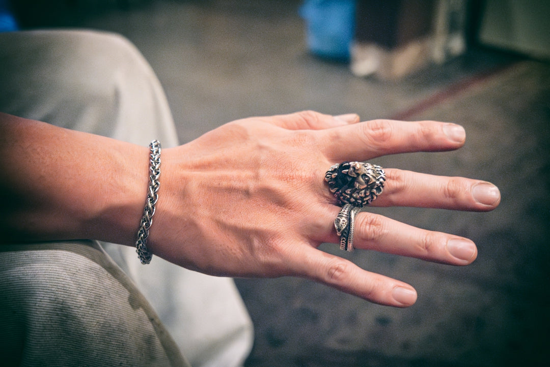 A hand is adorned with a bracelet and rings.