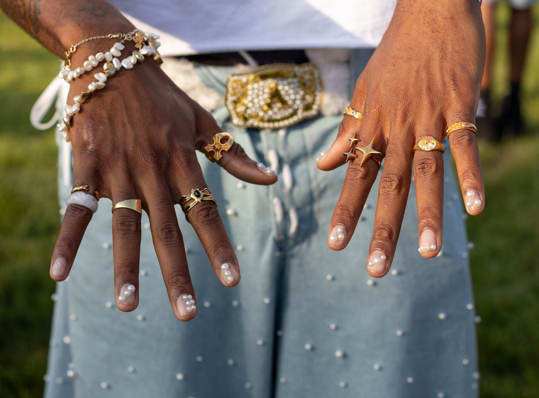 Hands showcase jewelry and patterned nails.