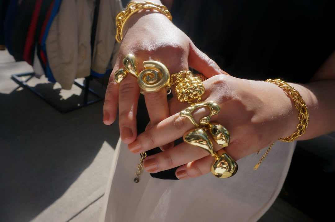 Hands adorned with chunky gold rings and bracelets.