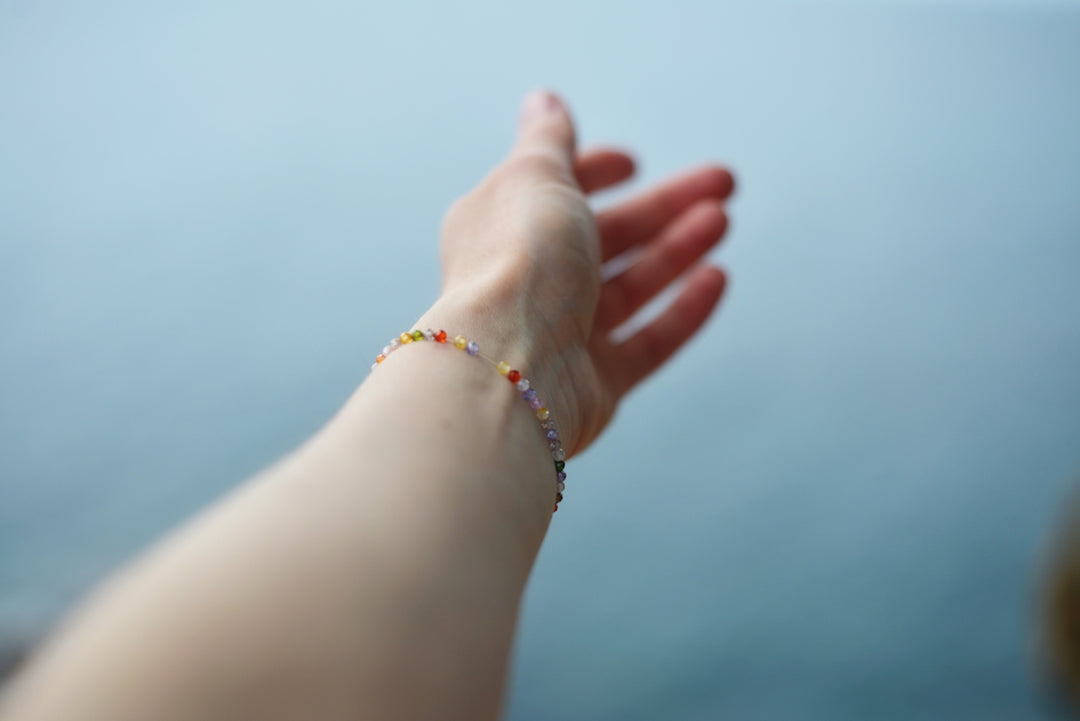 A hand with a colorful bracelet reaches out.